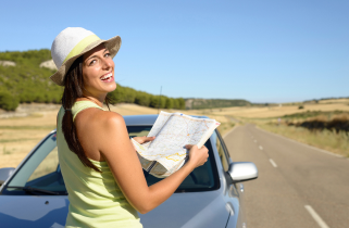 Woman Looking at a map in front of her car on the side of the road.