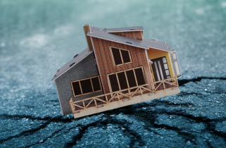 miniature of a house on cracked asphalt portraying the concept of an earthquake