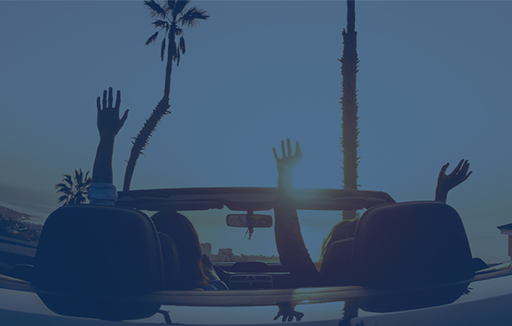 people parked in a convertible car at sunset near the beach